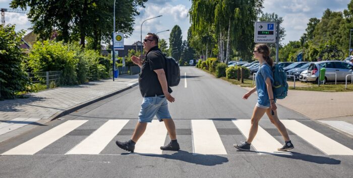 Michael Faber und Anna Scheffold von Realinzing Progress gehen über die Straße in Travemünde