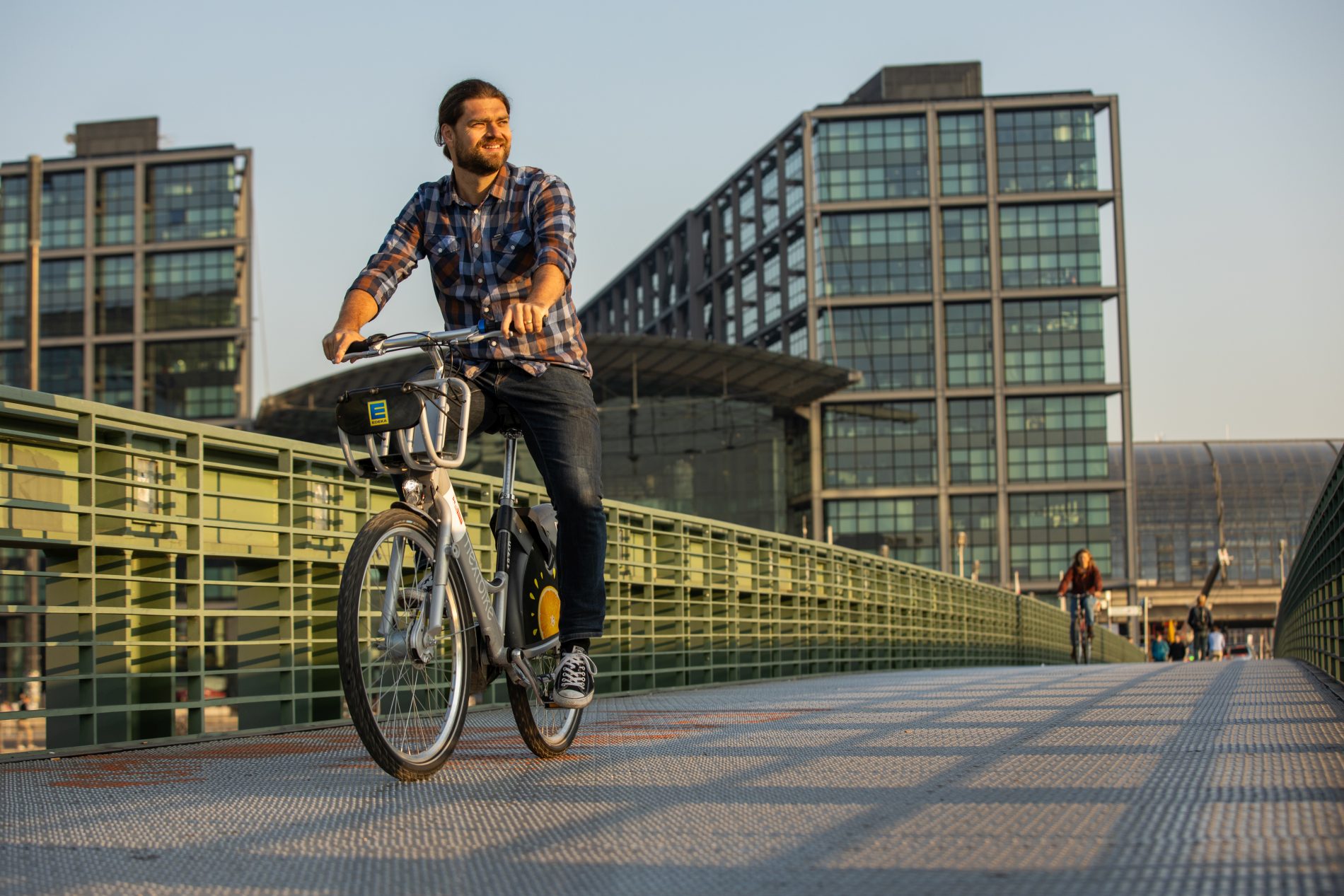 Martin Birchmeier | Realizing Progress fährt Fahrrad über eine Brücke im Sonnenaufgang